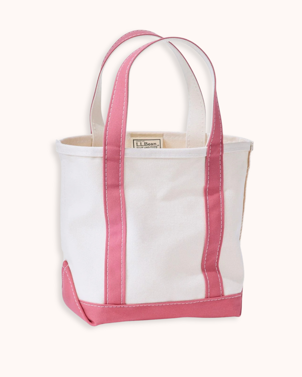 A white canvas tote bag with pink trim and handles, shown against a plain off-white background. A small brand label reading 'L.