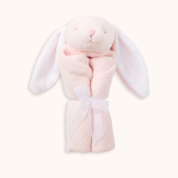 A light pink plush bunny-shaped towel wrap with long floppy ears and a white ribbon tied around the middle, shown on a plain off-white background.